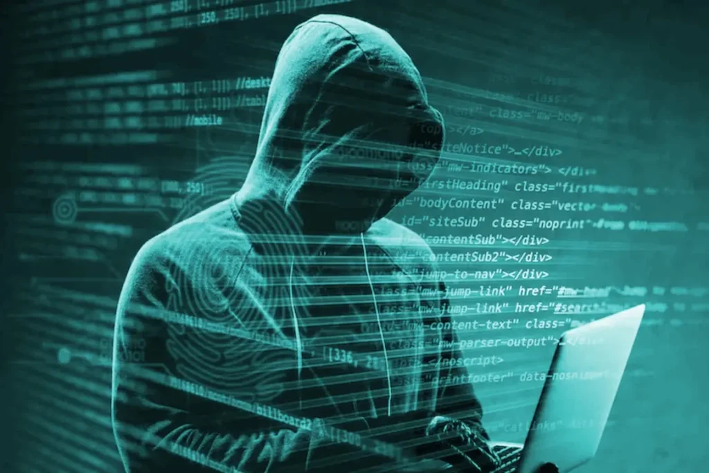 Shadowy hooded figure working amidst green code, illustrating the external threats neutralized by GODDRA's Cyber Defence services.